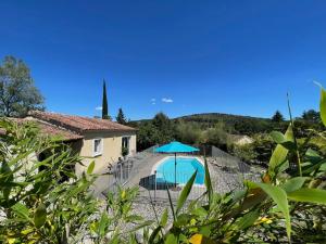 a villa with a swimming pool and a blue umbrella at Villa MIMOSA in Sampzon