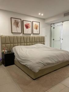 1 cama en un dormitorio con 3 cuadros en la pared en X Beach House en Al Khīrān