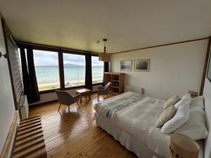 a bedroom with a bed and a view of the ocean at Weskar Lodge Hotel in Puerto Natales