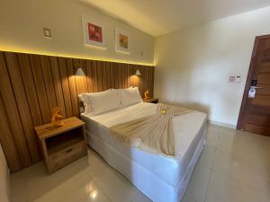a bedroom with a large bed and a night stand at Principe do Mutá Hotel Design in Santa Cruz Cabrália
