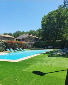 a swimming pool with green grass and chairs in a yard at Le Mas des Laurels in Chantemerle-lès-Grignan