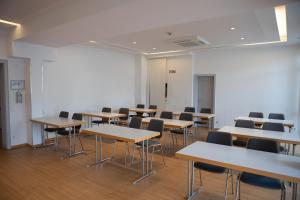 una clase con mesas y sillas en una habitación en pepb Schulungshotel, en Sarstedt