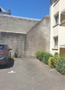 un coche aparcado en un estacionamiento junto a una pared en Très bel appartement Centre Vitré, en Vitré