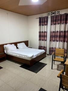 1 dormitorio con 1 cama y una ventana con cortinas en AIM Kanombe INN MOTEL en Kigali