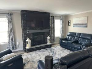 een woonkamer met een leren bank en een open haard bij Lake Life in Huddleston