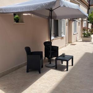a patio with chairs and an umbrella and a table at NICOLE LUXURY ROOMS in Fondi