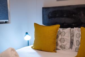 uma cama com uma almofada amarela e 2 almofadas brancas em The Millennial Prime Umhlanga em Durban