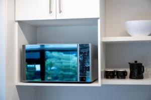 um micro-ondas em armários de cozinha brancos em The Millennial Prime Umhlanga em Durban