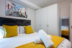 um quarto com uma cama branca e almofadas amarelas em The Millennial Prime Umhlanga em Durban