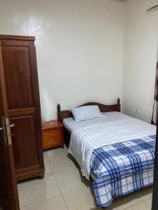 1 dormitorio con 1 cama y armario de madera en AIM Kanombe INN MOTEL en Kigali