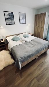 duże łóżko w sypialni z drewnianą podłogą w obiekcie Olimpijska pokoje w Szczyrku