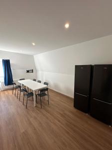 a dining room with a white table and black appliances at Ar Living Frankfurt Königsteinerstr in Frankfurt/Main