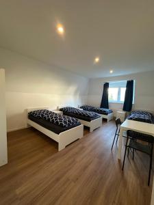 three beds in a room with wooden floors at Ar Living Frankfurt Königsteinerstr in Frankfurt/Main