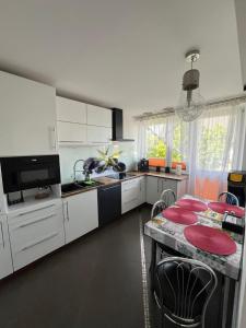 a kitchen with white cabinets and a table with red chairs at Apartament Night Premium Krakow in Krakow