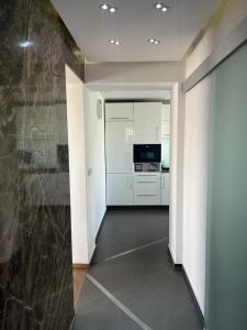 um corredor com uma cozinha com armários brancos e uma parede em Apartament Night Premium Krakow na Cracóvia