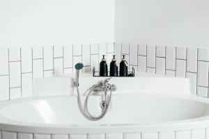 a bath tub with three bottles on a shelf above it at Kanaal kooi in Upington