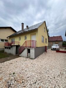 a yellow house with a red balcony and a driveway at Studio Apartman Josip in Gospić