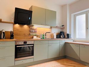 a kitchen with white cabinets and a tv on the wall at cardia homes Ferienwohnung Erfurt-Hopfenberg - Terrasse - Wlan - Vollausstattung in Erfurt