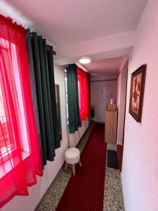 a hallway with red and green curtains and a red carpet at Studio Apartman Josip in Gospić
