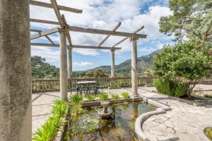 a garden with a pond and a wooden pergola at ses llebres in Bunyola