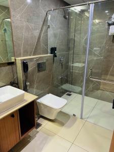 a bathroom with a shower and a toilet and a sink at park royal hotel in Dwarka