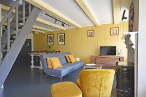 a living room with a blue couch and yellow chairs at EAstay in Oostermeer