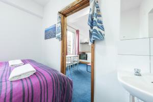 Schlafzimmer mit einem Bett, einem Waschbecken und einem Spiegel in der Unterkunft Pax Lodge in London