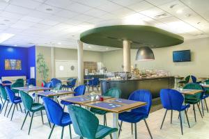 un restaurante con mesas y sillas azules y un bar en Campanile Łódź en Lodz