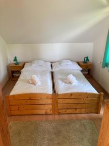 2 camas en una habitación con sábanas y almohadas blancas en Vila Marko, en Nová Lesná