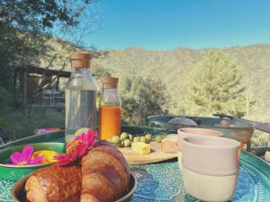 a table with a plate of bread and bottles of cider at Ikkyo Lodge in Saumane