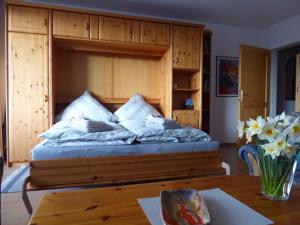 a bedroom with a bed with a wooden headboard and a table at Ferienwohnung Am Kräutergarten - mit Pool, Sauna und Garage in Missen-Wilhams