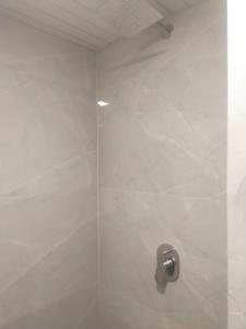 uma casa de banho com um chuveiro com azulejos brancos em Hotel airport annex em Mumbai