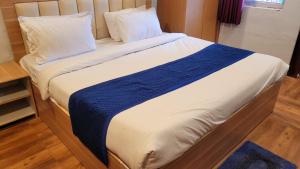 uma cama grande com lençóis e almofadas azuis e brancos em Swastik Resort Vrindavan em Vrindavan