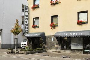 a city hotel building with flowers in the windows at City Hotel Fellbach 24H CHECK-IN in Fellbach