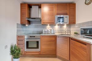 a kitchen with wooden cabinets and stainless steel appliances at Luxury One Bedroom Apartment St Pauls Cathedral in London