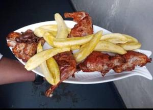 a person holding a plate of food with french fries at AIM Kanombe INN MOTEL in Kigali