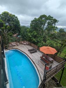 a swimming pool with a table and an umbrella at Rainforest Lodge del Rio in Portobelo