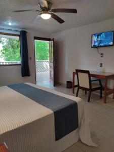 a bedroom with a bed and a desk and a ceiling fan at Hotel Puerta Chichen in Chichén-Itzá