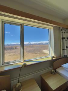 twee ramen in een kamer met een bed en een tafel bij Vökuholt Lodge in Laxamýri