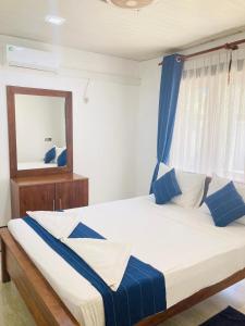 Yatinuwara Bungalow في أنورادابورا: غرفة نوم بسرير كبير ومخدات زرقاء وبيضاء