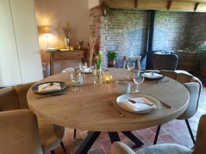 una mesa de madera con platos y copas de vino. en B&B Den Bruynen Bergh, en Beernem