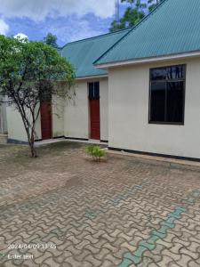 a white house with a green roof at A 4G LODGE in Mugumu