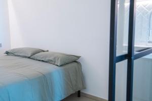 un letto con due cuscini, posto accanto a una finestra. di Appartamento - Mondovì a Mondovì