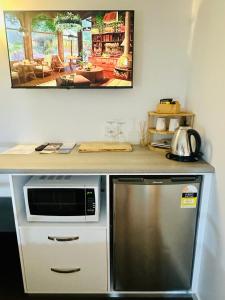 a kitchen with a counter with a microwave and a refrigerator at Sunbird Suite in Palm Cove in Palm Cove