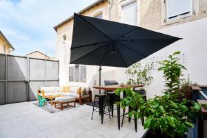 eine Terrasse mit einem Tisch und einem schwarzen Sonnenschirm in der Unterkunft Maison de ville moderne climatisée avec piscine in Morières-lès-Avignon