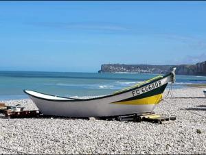 a boat sitting on a rocky beach near the water at Chambre double privée chez l'habitant, très bon emplacement avec parking privé et grand jardin in Dieppe