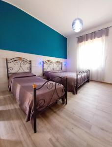 two beds in a room with a blue wall at RoofTop Home Stagnone in Marsala