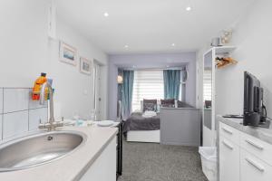a bathroom with a sink and a bedroom with a bed at Boutique Studio Apartment By My Getaways in Rottingdean