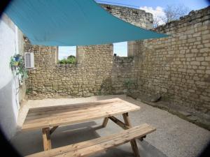 a wooden picnic table in front of a brick wall at L'instant détente in Saint-Léger-de-Montbrillais