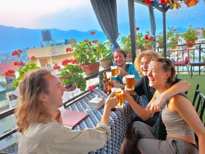 een groep mensen die aan een tafel bier drinken bij Yog Hostel- Rooftop Yoga & Backpacker Social Stay in Thamel, Kathamndu in Kathmandu